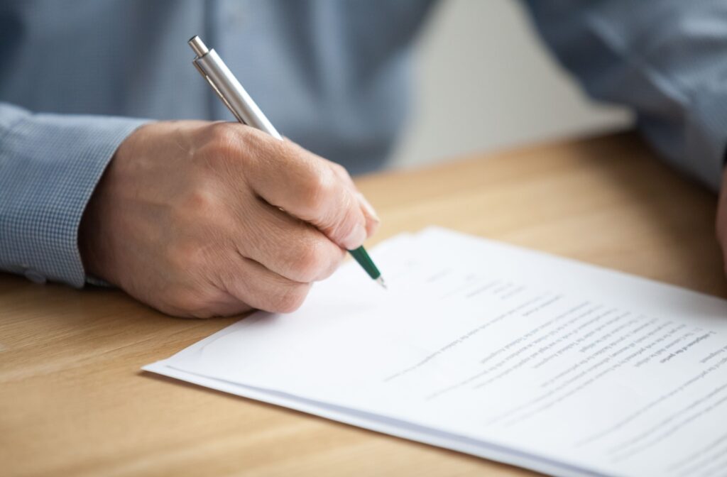 A close-up of a senior with dementia signing legal documents